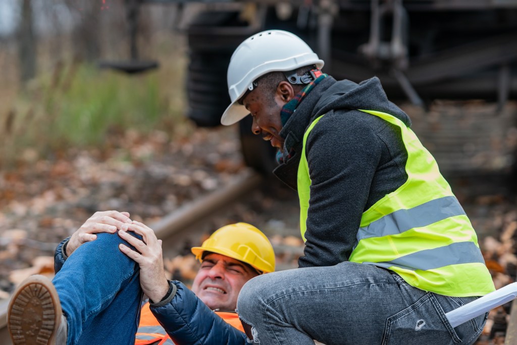 mechanic helping injured colleague railroad track
